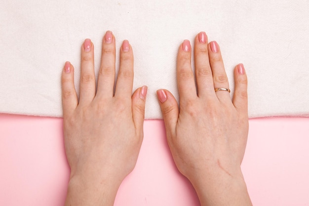 Foto las manos de una niña con uñas bien cuidadas y desordenadas y regeneradas con gel polaco y cubiertas con g