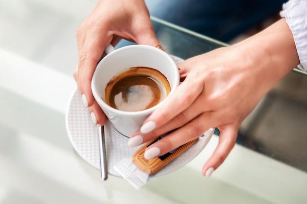 Foto manos de niña cuidada sosteniendo una taza de café