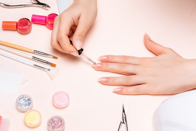 Manos de una niña haciendo una manicura en casa, primer plano de las manos. la vista desde arriba