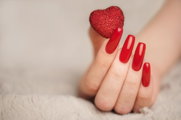 Manos de niña con manicura roja y corazón decoratine.