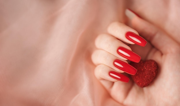 Manos de niña con manicura roja y corazón decoratine.