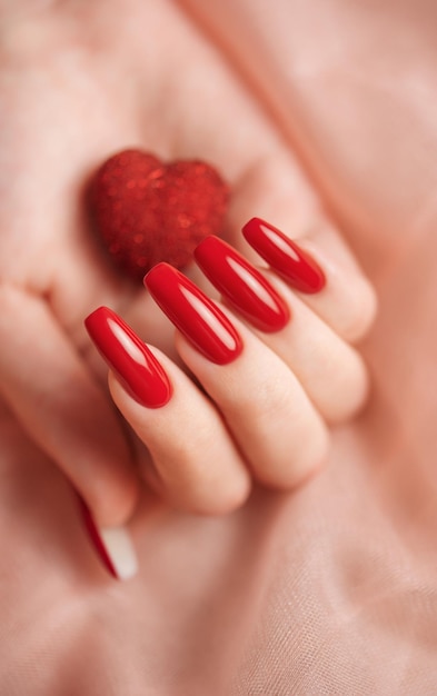 Manos de niña con manicura roja y corazón decoratine.