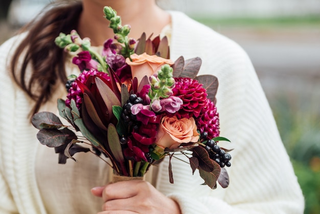 Manos de niña con ramo de flores en estilo boho rústico.