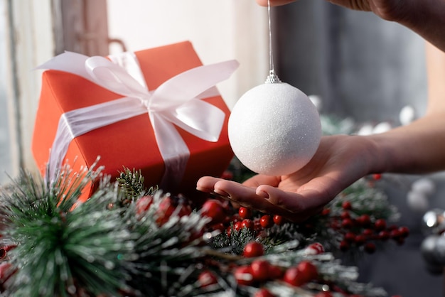 Foto las manos de la niña y el regalo rojo de año nuevo en el fondo de las decoraciones navideñas