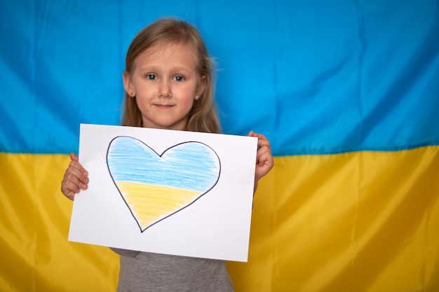 Manos de niña sosteniendo pancarta con corazón azul amarillo dibujado en la bandera ucraniana Detener la guerra quedarse con Ucrania