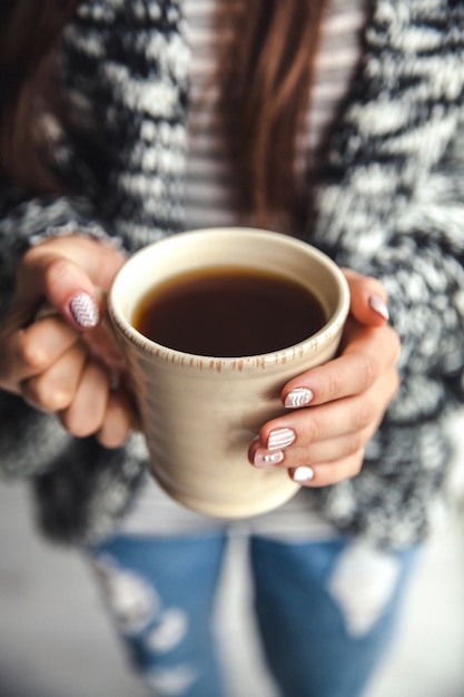 Manos de niña sosteniendo una taza de café y