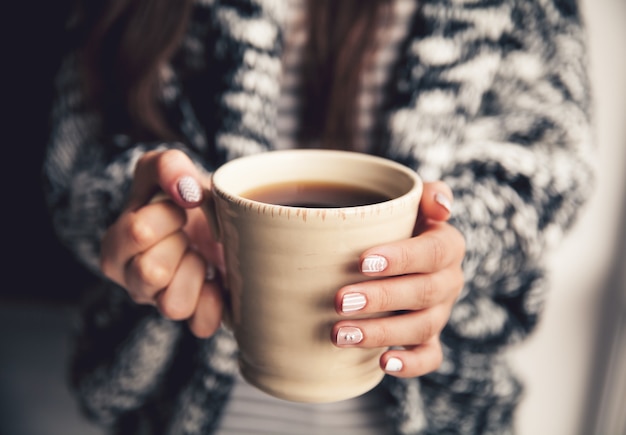 Manos de niña sosteniendo una taza de café