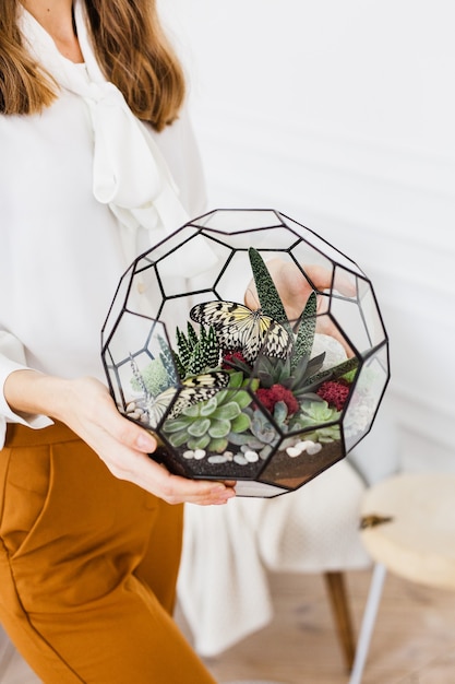 Las manos de la niña sostienen un florario, una forma de flores hechas de vidrio y metal.