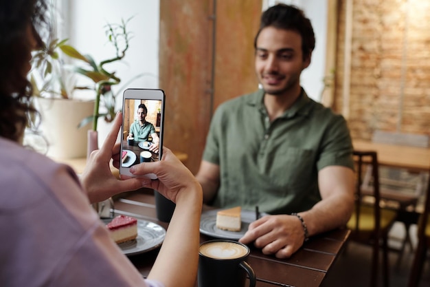 Manos de niña con teléfono móvil tomando fotos de su novio feliz