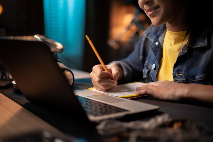 Foto manos de niña tomando notas con lápiz en cuaderno