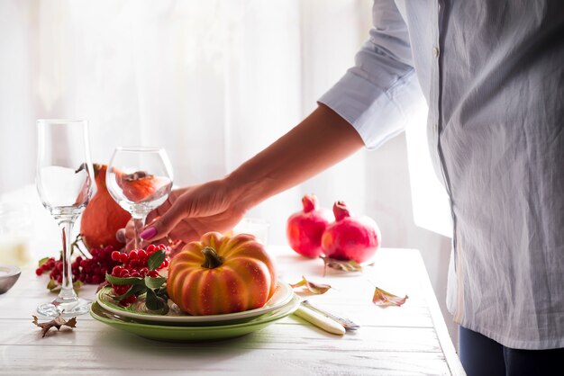 Las manos de las niñas preparan la mesa festiva de Acción de Gracias