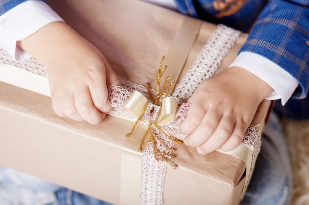 Manos del niño con caja de regalo. Copie el espacio.