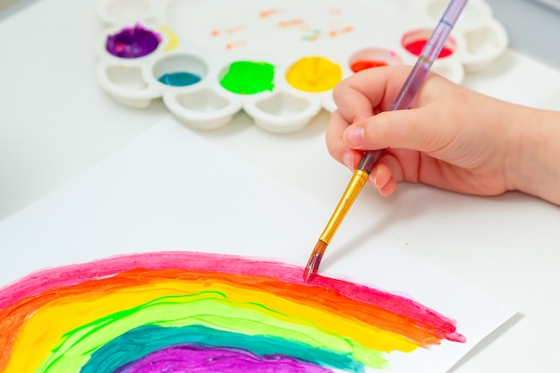 Las manos del niño dibujando arco iris.