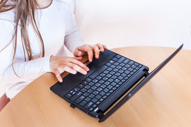 Manos del niño escribiendo en el teclado de la computadora portátil