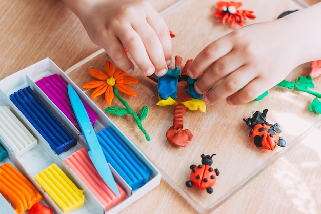 Las manos del niño esculpen figuras de plastilina suave. Clases educativas y entretenidas con niños. De cerca. Vista superior