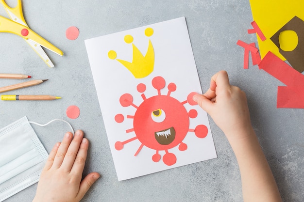 Las manos del niño hacen un collage de tarjetas con el virus corona covid-19