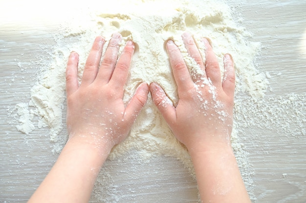 Foto manos de un niño en harina. el niño está cocinando.