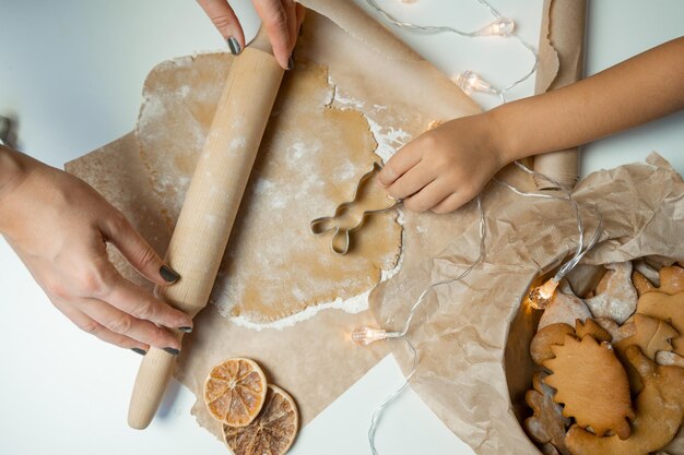 Las manos del niño y la madre preparan galletas con la masa.