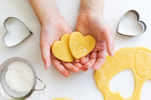 Manos de niño con masa de corazón. Proceso de cocción