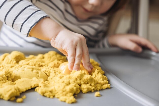 Manos de niño moldeando con arena cinética mágica Niño lindo jugando con arena cinética Desarrollo de habilidades motoras finas Educación sensorial temprana Terapia de arte con arena Actividades Montessori