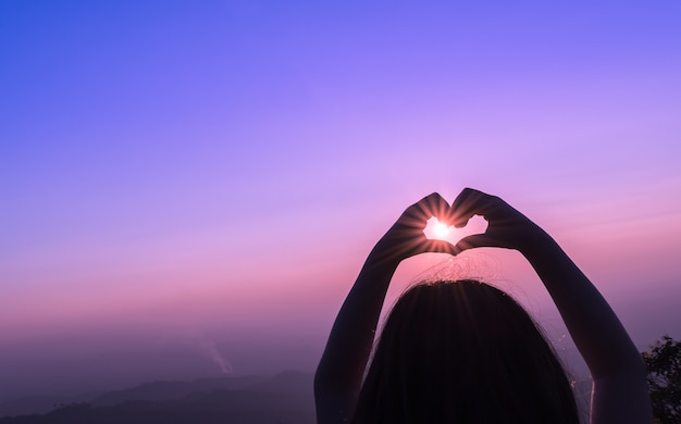 Foto las manos de niño muestran el símbolo del corazón en forma, el concepto de estilo de vida y sentimientos con la naturaleza de la luz del atardecer en backg