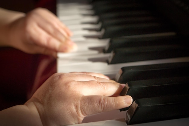 Manos de niño en el piano.