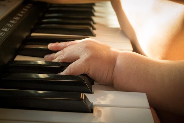 Manos de niño en el piano.