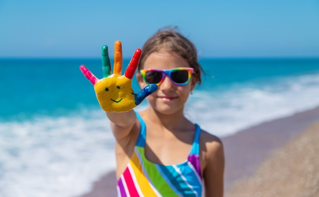 Manos de niño pintadas con pinturas sobre el mar. Enfoque selectivo. Niño.