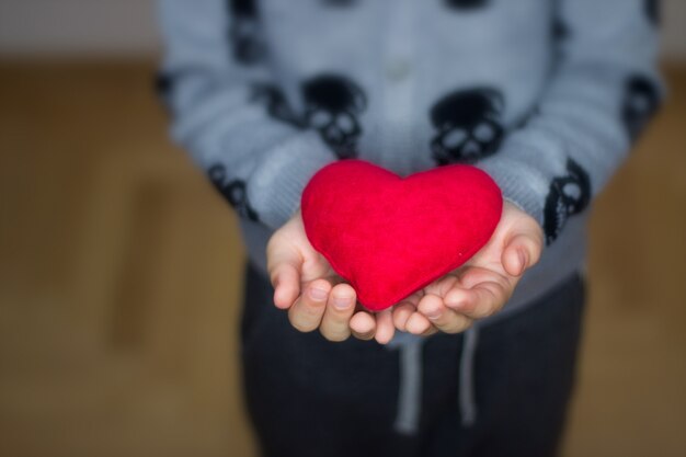 Manos de niño sosteniendo corazón rojo