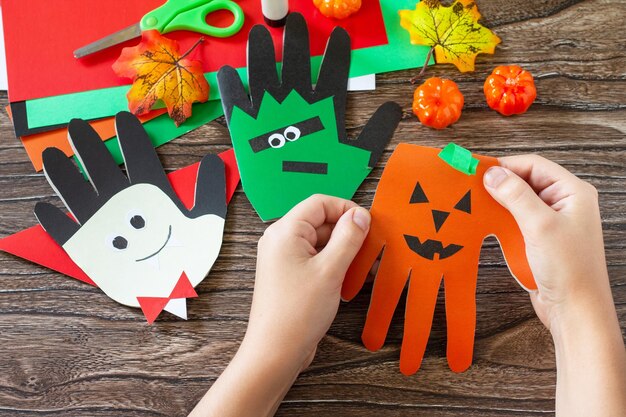 En manos de un niño Tarjeta de felicitación de halloween en la mesa de madera Proyecto de creatividad infantil