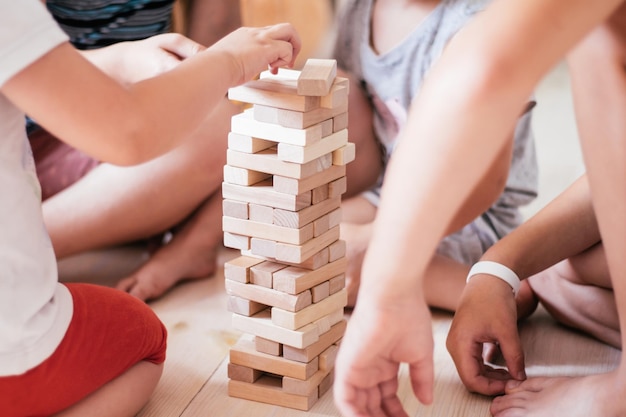 Las manos de los niños borrosas juegan con la torre, hecha de bloques de madera