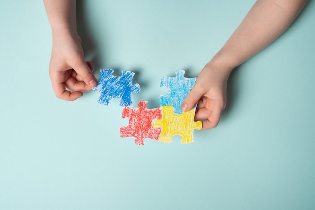 Las manos de los niños colocando un rompecabezas de colores símbolo del Día Mundial de la Concienciación sobre el Autismo