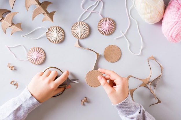 Las manos de los niños cortan círculos de cartón para las decoraciones hechas a mano de Navidad DIY Vista superior