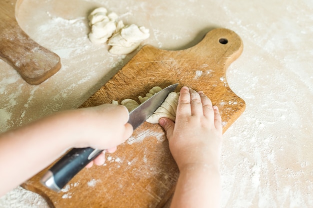 Manos de niños cortando masa cruda