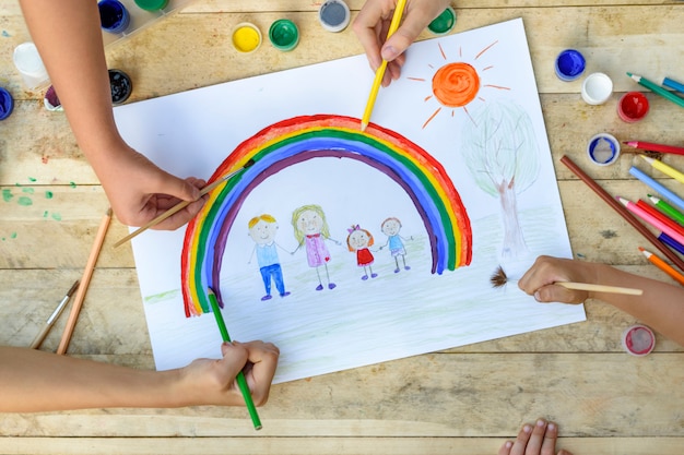 Las manos de los niños dibujan en una hoja de papel