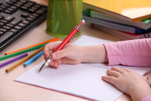 Manos de los niños dibujando en el cuaderno en el primer plano del escritorio