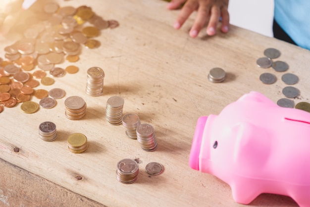 Las manos de los niños están ayudando a poner monedas en la hucha sobre fondo blanco.