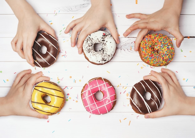 Las manos de los niños están quitando los coloridos donuts.