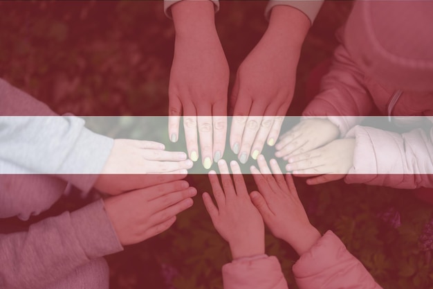 Manos de niños en el fondo de la bandera de Letonia Concepto de patriotismo y unidad de Letonia