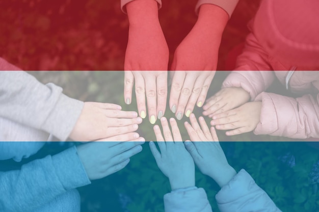 Manos de niños en el fondo de la bandera de Luxemburgo Concepto de unidad y patriotismo luxemburgués