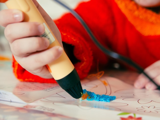 Las manos de los niños hacen una artesanía usando una pluma de impresión 3D Una niña dibuja con una pluma 3D