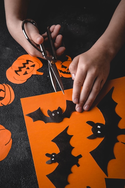 Las manos de los niños hacen una calabaza con sus propias manos preparándose para Halloween