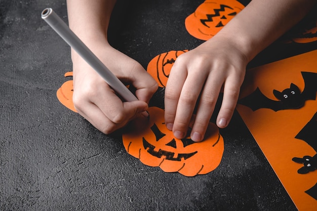 Las manos de los niños hacen una calabaza con sus propias manos preparándose para Halloween