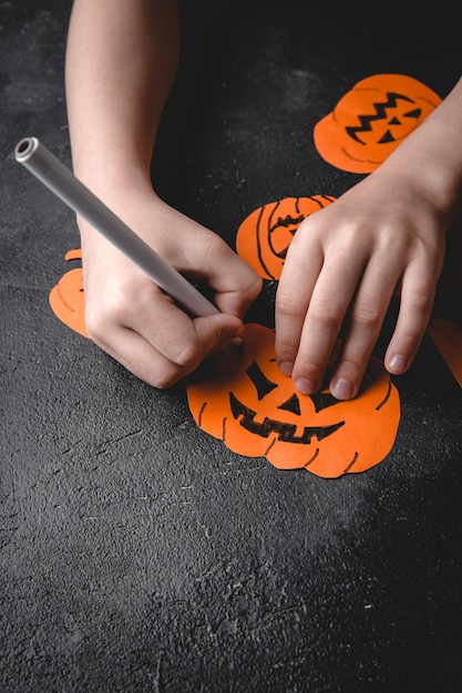 Las manos de los niños hacen una calabaza con sus propias manos preparándose para Halloween