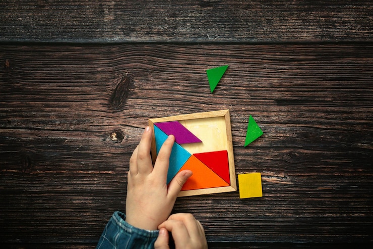 Foto las manos de los niños y el juego de rompecabezas de madera sobre un fondo de madera vista superior el concepto de juguetes educativos independientes para niños en el pensamiento escolar