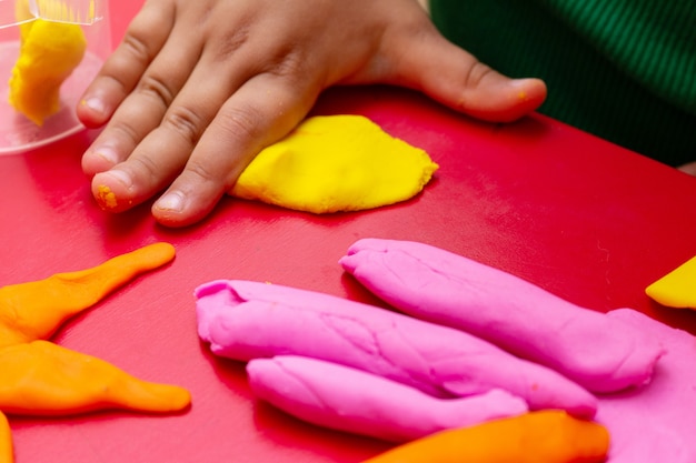 Las manos de los niños moldean el primer colorido de la masa. Concepto de educación infantil