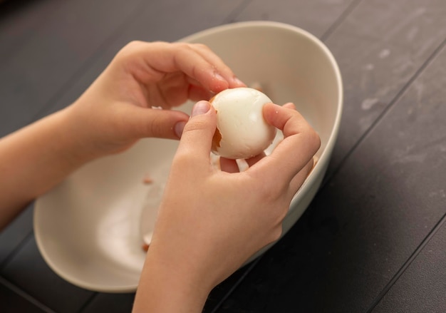 manos de niños pelando un huevo cocido en la cocina tiro natural