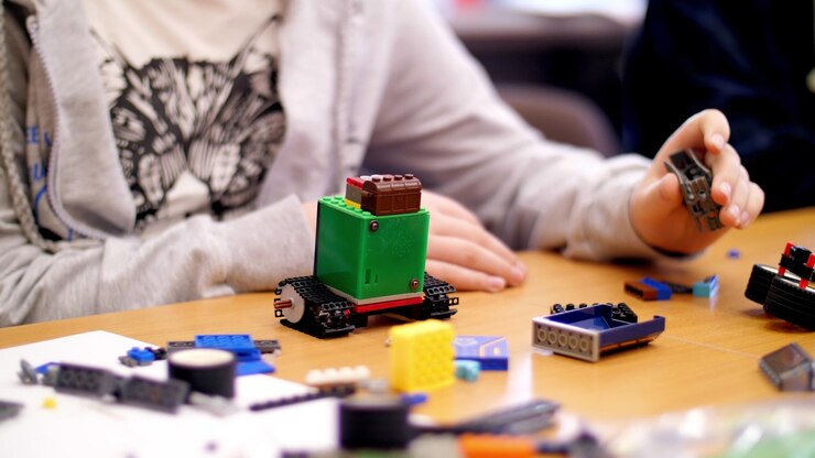 Foto las manos de los niños de primer plano sostienen una pequeña máquina robótica multicolor
