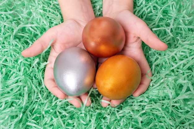 Manos de niños sosteniendo huevos multicolores en un papel verde como fondo de hierba Concepto de Pascua