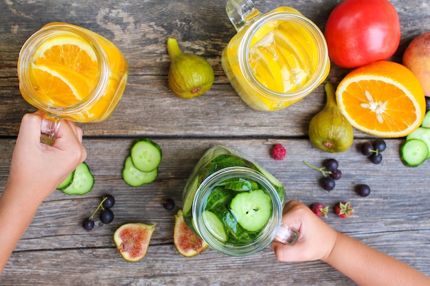 Las manos de los niños toman bebidas con fondo de frutas y verduras.